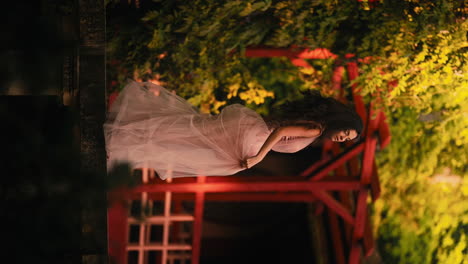 Alegre-Y-Elegante-Mujer-Morena-Sonriendo-Y-Agitando-Un-Vestido-Rosa-En-El-Jardín