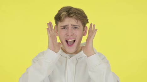 joven gritando, gritando en el fondo amarillo