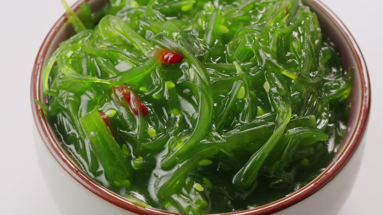Japanese wakame chuka fermented food. Close-up on a detail of Hiyashi Wakame Chuka or seaweed salad or seaweed with sesame seeds on a plate. Top view. Seafood background. Health concept.