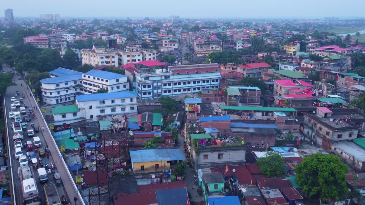 Siliguri city densely populated residential neighbourhood with historical hillcart road traffic movement under hazy sky, West Bengal, Establishing drone shot