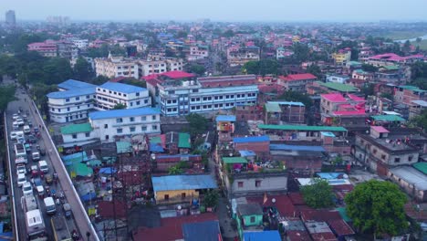 siliguri city densely populated residential neighbourhood with historical hillcart road traffic movement under hazy sky, west bengal, establishing drone shot