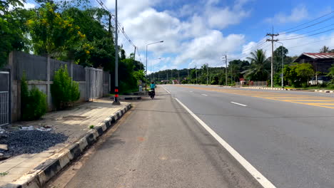 una ciclista solitaria montando a lo largo de una carretera urbana vacía en la provincia de nan, tailandia