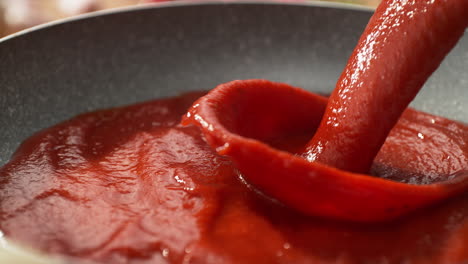 tomato sauce pouring into the pan with passata - cooking pizza sauce or preparing spaghetti bolognese in slow motion