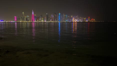 qatar doha dubai city landscape at night reflection of light and tower high building skyscrapers on sea water surface small wave colorful lights in darkness dark sky modern city in middle east asia