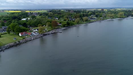 Felsiges-Ufer-An-Einem-Ruhigen-Strand-Mit-Küstenstadt-Im-Kreis-Skane,-Südlich-Von-Schweden