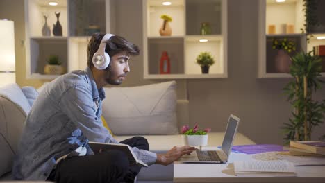 male student listening to music and studying at night.