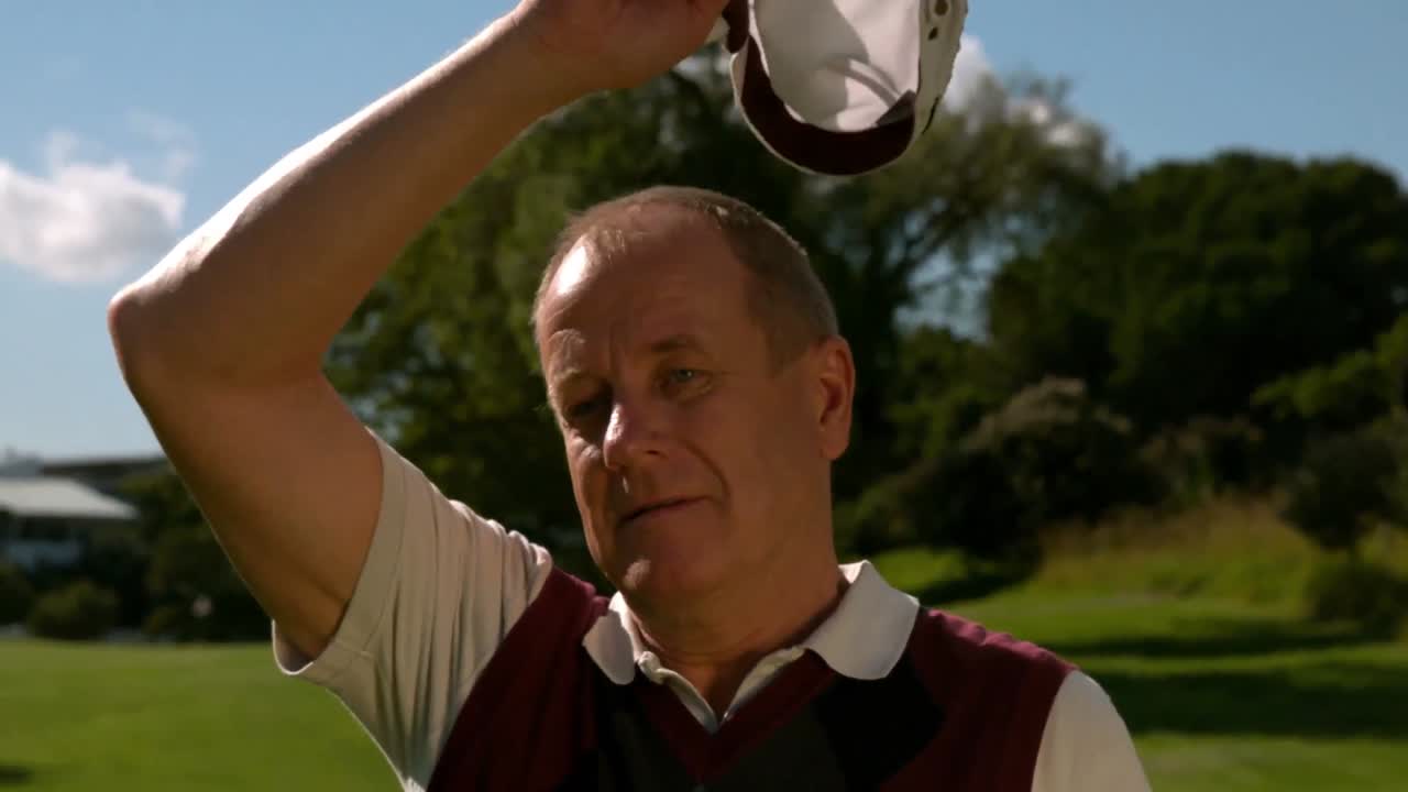 golfista maduro quitándose la gorra en un día caluroso