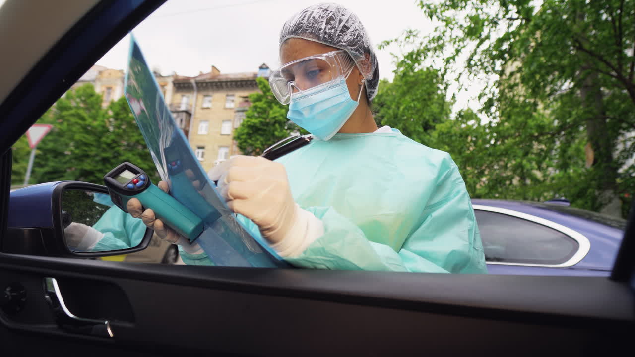 trabajador sanitario realizando una comprobación de temperatura fuera de un automóvil