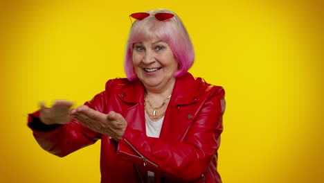 una elegante mujer mayor con cabello rosa y chaqueta de cuero roja