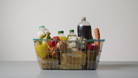 foto de estúdio de alimentos básicos na cesta de compras de arame de supermercado