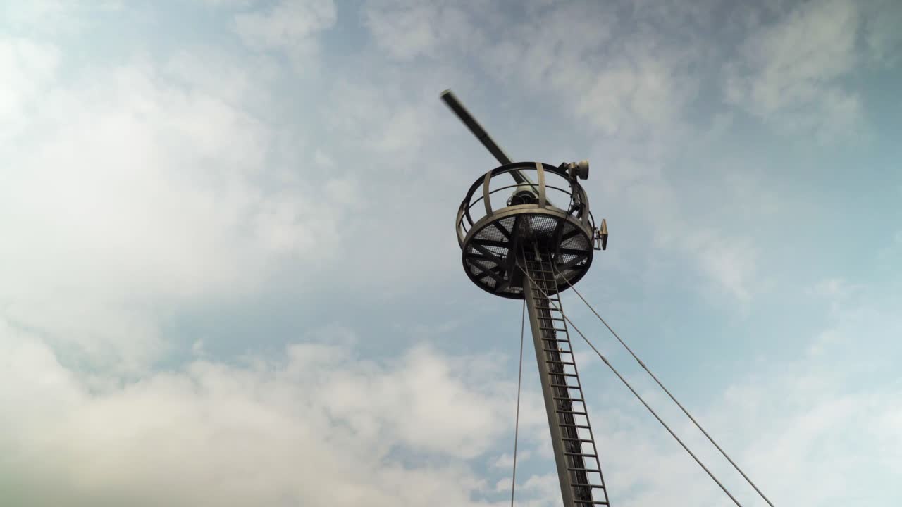 A rotating radar tower is scanning the area for flights and naval ships around the area in a cloudy day during daytime as the clouds move