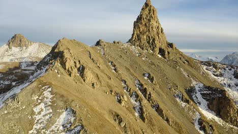 toma aérea pasando cerca del terreno y subiendo por encima de la cumbre rocosa "la maya" que revela los colores del paisaje alpino otoñal al atardecer, valais - suiza