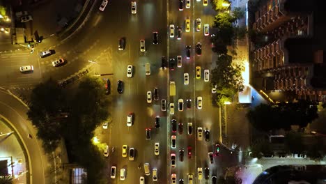 aerial shot of rush hour traffic in guangzhou, china, at night. cars and taxis move through the bustling city streets, illuminated by streetlights and surrounding buildings.