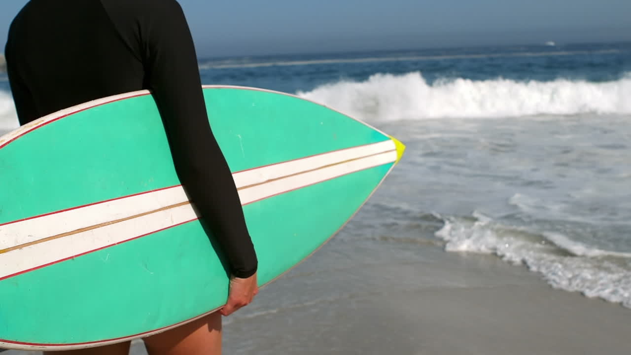 mujer con una tabla de surf en la playa