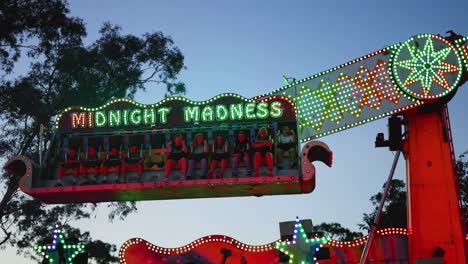 amusement park ride swings and lights up at dusk