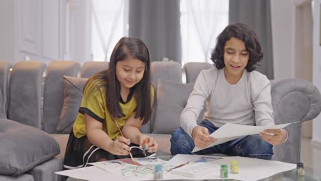 Happy-Indian-boy-finishes-his-drawing-and-shows-it-to-sister