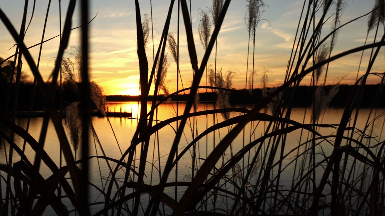 puesta de sol colorida y espectacular cielo naranja sobre un lago tranquilo con muelle en la distancia
