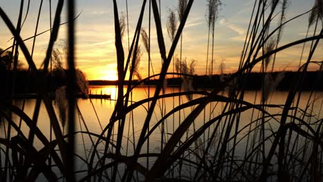 Farbenfroher-Sonnenuntergang-Und-Dramatischer-Orangefarbener-Himmel-über-Einem-Friedlichen-See-Mit-Dock-In-Der-Ferne