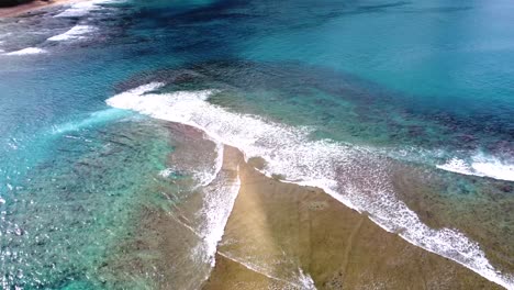 Aerial-view-of-waves-crashing-over-tropical-coral-reef-in-Kauai,-Hawaii,-USA