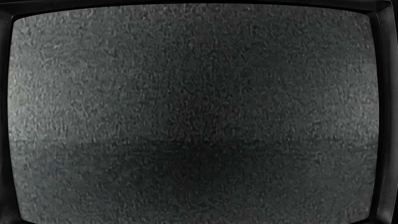 Starting with grey noise, static pattern filling curved CRT television screen in interior close-up