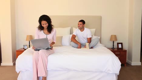 young couple sitting on their bed sharing a laugh