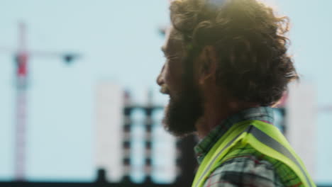 close-up of a bearded man in a high-visibility vest at a work site