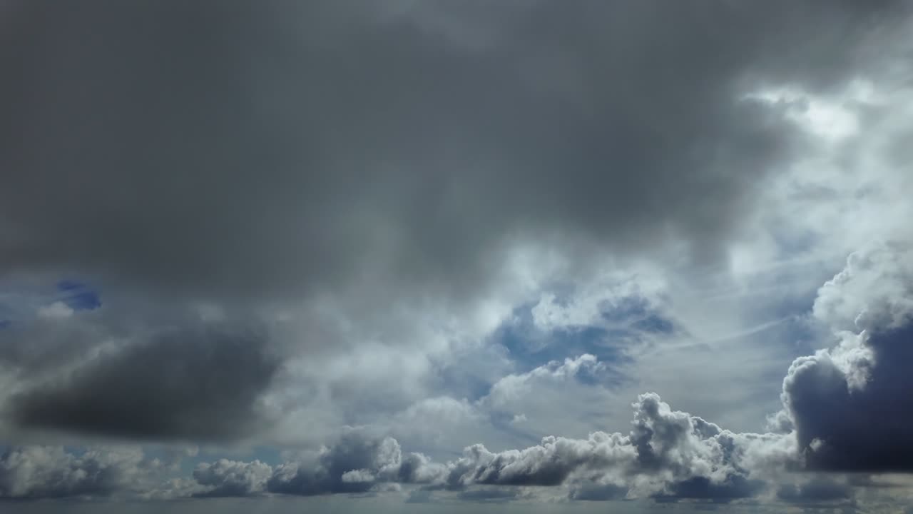 an immersive aerial view through the pilot’s eyes while flying under a layer of threatening cumulus clouds in a blue sky, with a radiant sun shinning above in the sky. Ultra realistic 4K footage.