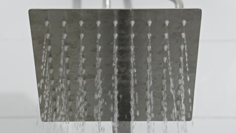 close-up view of a silver colored rain shower being turned on and water starts to rain