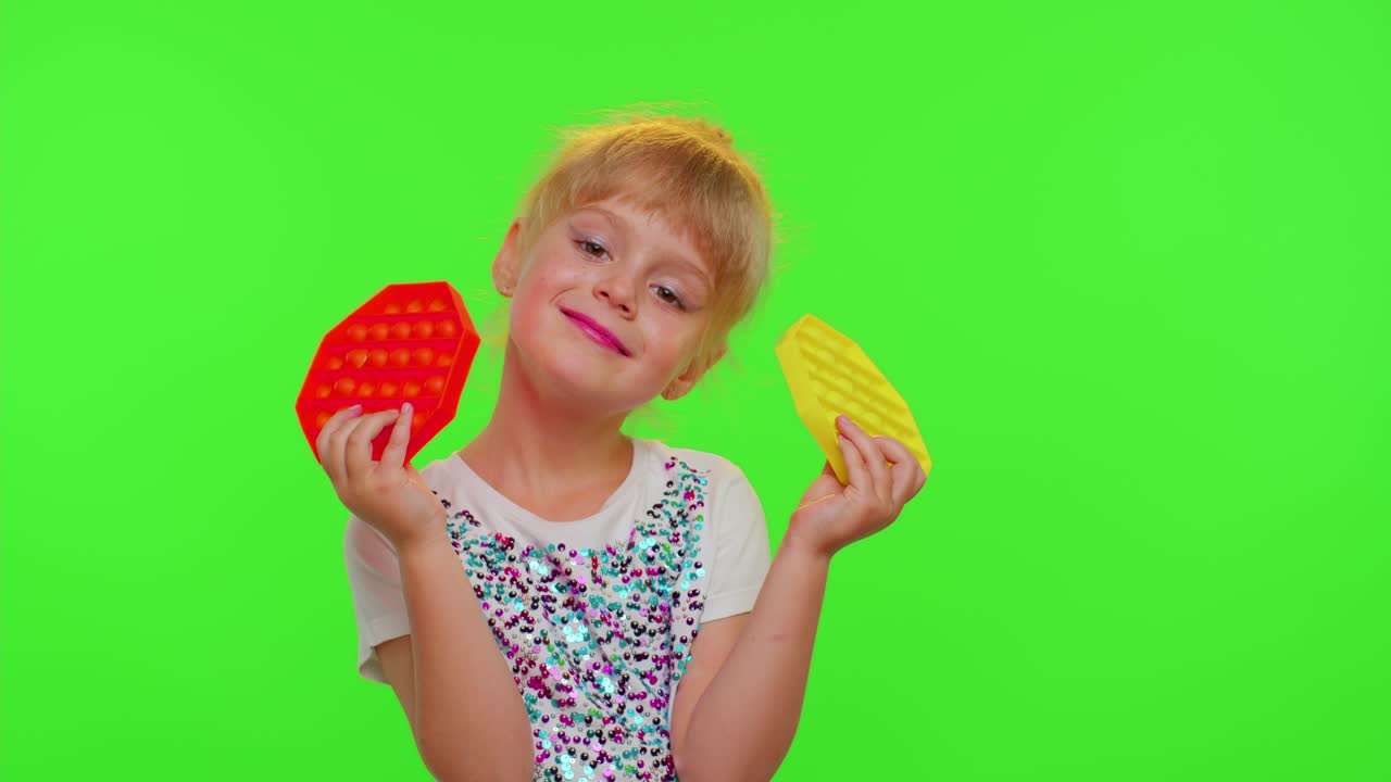 niña escondiéndose detrás de dos pop it juguetes sensoriales contra el estrés, burbujas blandas juego de moda, contra el estrés