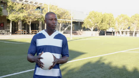 holding soccer ball, african american man standing on sports field, looking serious, copy space