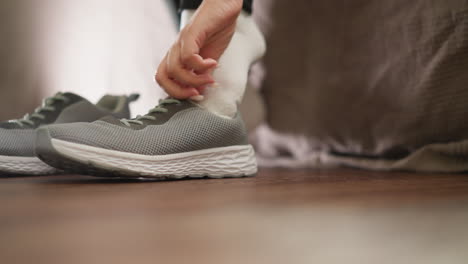 woman puts on sneaker at home closeup. active sportswoman tries on sneaker for future training helping with hands slow motion. sporting clothes