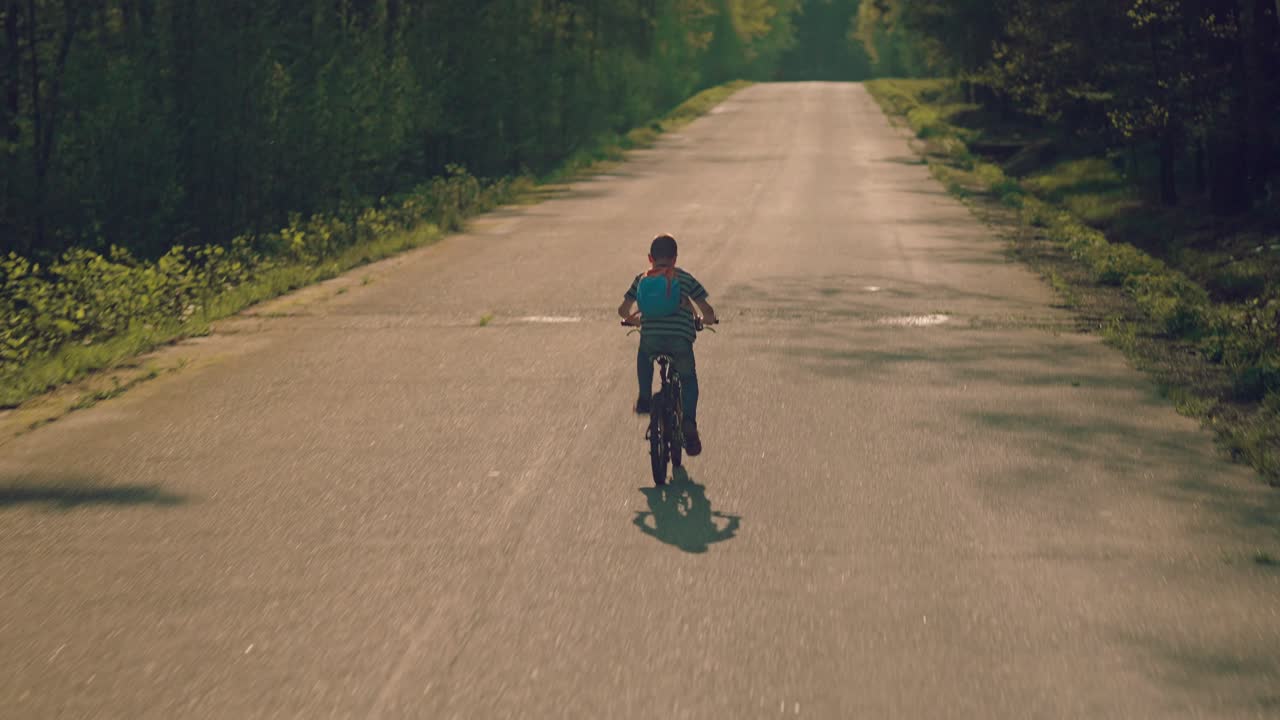 자연을 통해 도로에서 자전거를 타는 어린 소년