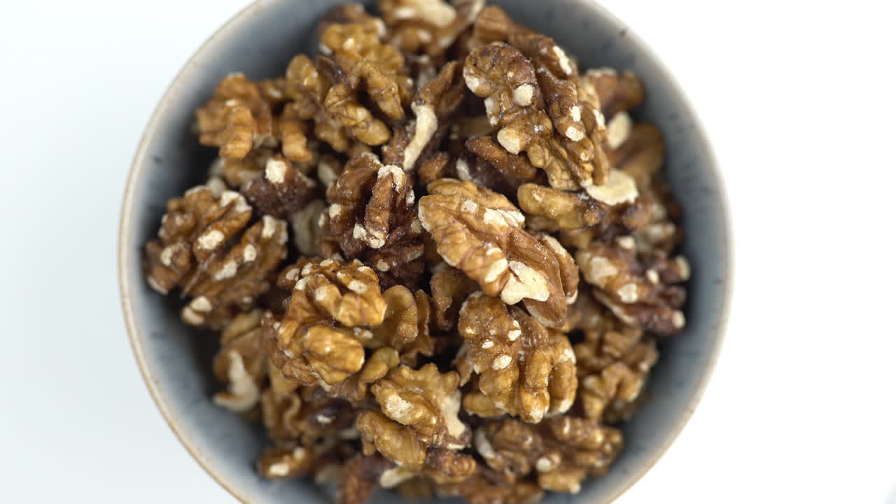 Ciotola di noci ripresa dall'alto. Noci in rotazione. Cibo vegano crudo a base vegetale e proteico. Alimenti sani e vegetariani. Ingredienti per una colazione sana. Ripresa macro 4K di ingredienti nutrizionali.