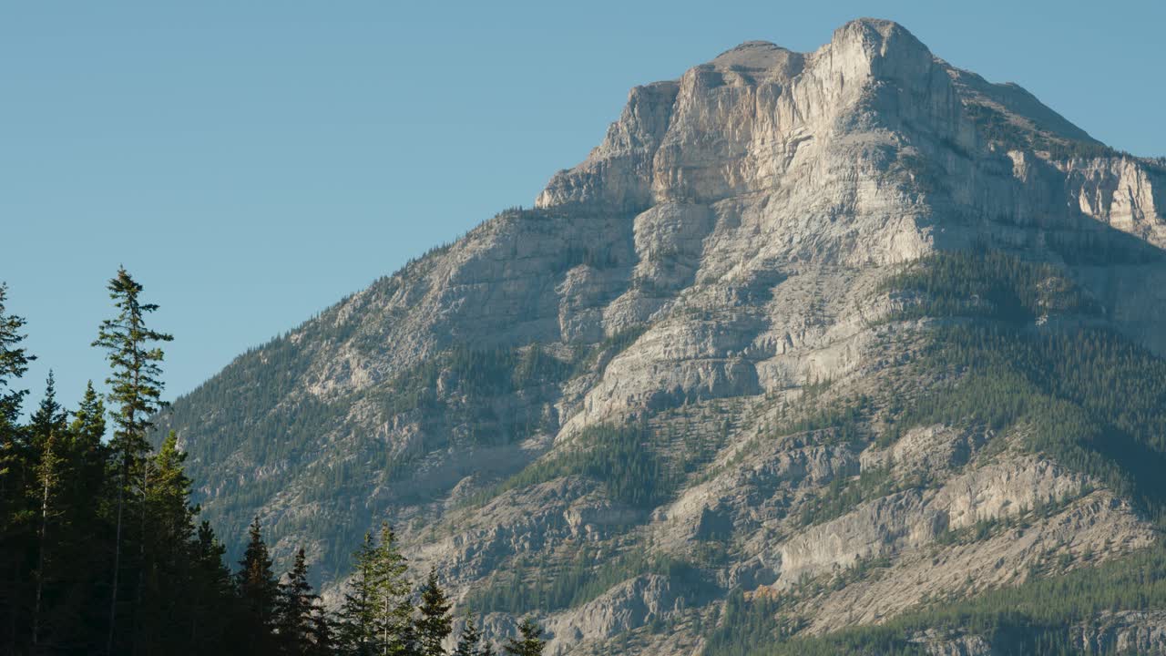 The A Large Cliff Face of the Canadian Rocky Mountains Tower over Cars on Canada's Trans Canada Highway One