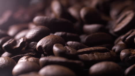 fingers picking up dark brown fresh coffee beans, close up