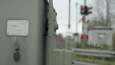 close-up of a railroad switch mechanism with instructions, blurred train signal in background