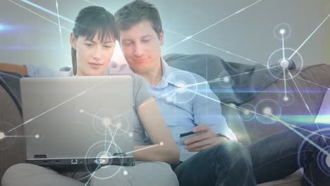 animación de una red de conexiones a través de una pareja haciendo pagos en línea con tarjeta de crédito utilizando una computadora portátil