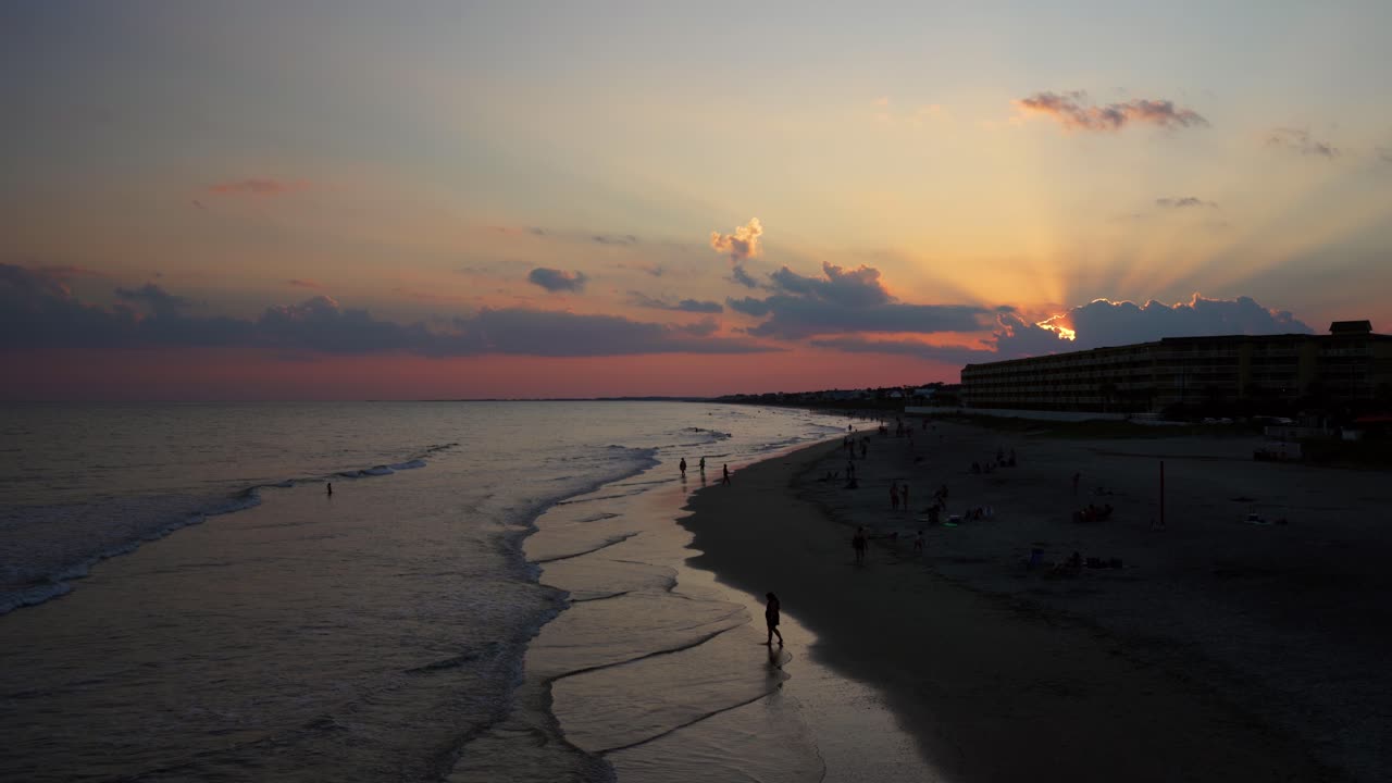 los rayos de dios brillan a través de nubes oscuras al atardecer en folly beach, carolina del sur
