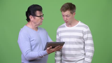 hombre guapo anciano y hombre guapo joven usando tableta digital juntos