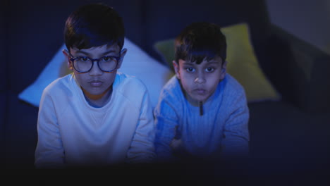 Front-View-Of-Two-Young-Boys-At-Home-Having-Fun-Playing-With-Computer-Games-Console-On-TV-Holding-Controllers-Late-At-Night