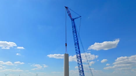 tower of wind turbine with large crane - construction of windmill in austria - aerial drone shot