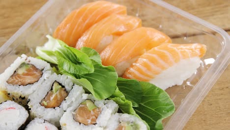 rollos de sushi con salmón en un recipiente de plástico