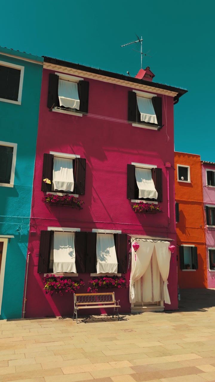 Casas de Burano em vermelho vivo e turquesa sob a luz do sol