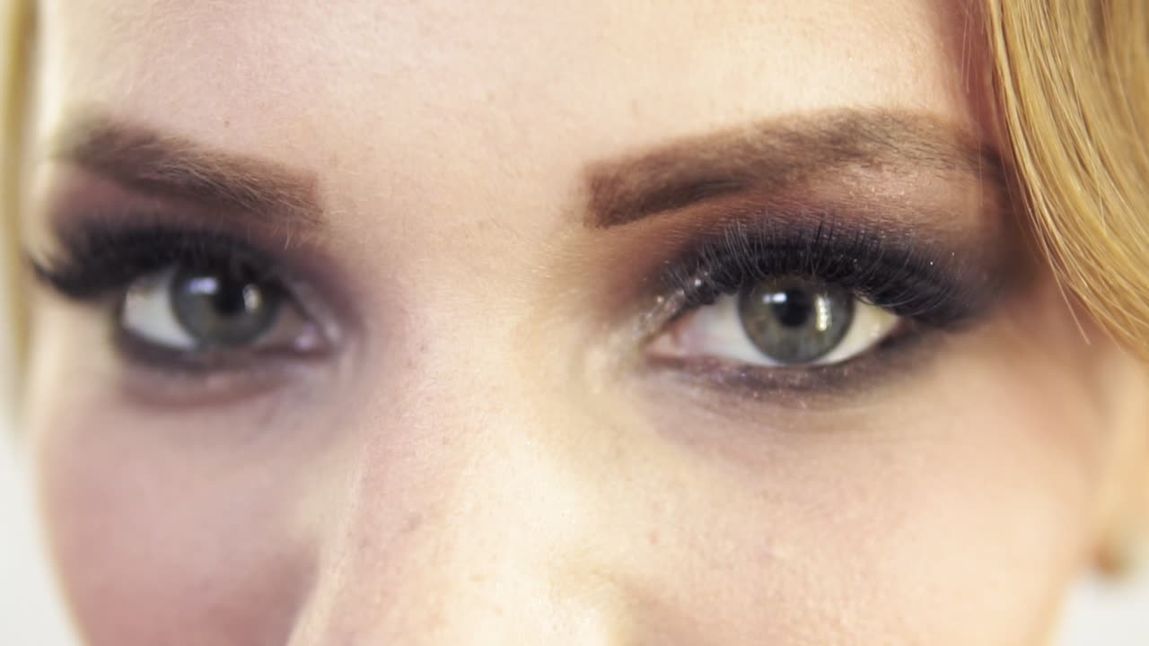 vista de cerca del maquillaje aplicado en los ojos de un modelo. modelo con pestañas falsas abriendo los ojos y mirando a la cámara