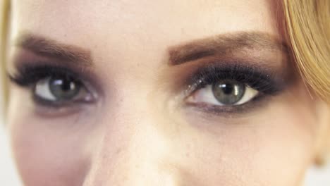 vista de cerca del maquillaje aplicado en los ojos de un modelo. modelo con pestañas falsas abriendo los ojos y mirando a la cámara