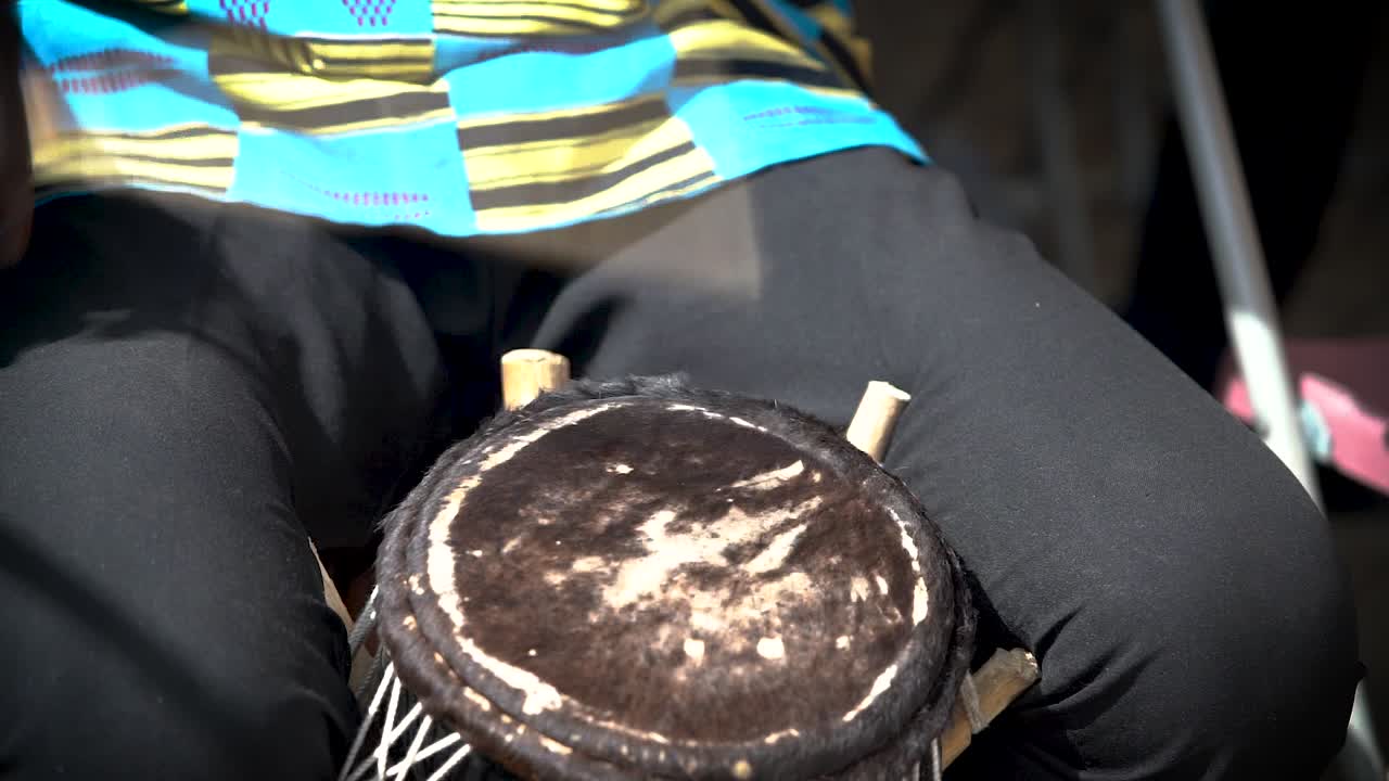 una toma de primer plano filmada en cámara lenta muestra a un solo baterista tocando un parche de tambor tradicional de piel de animal en un festival en ghana, áfrica occidental.