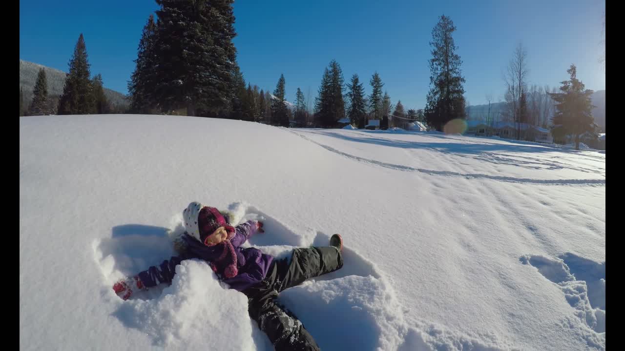 niño haciendo ángeles de nieve en la nieve durante el invierno 4k