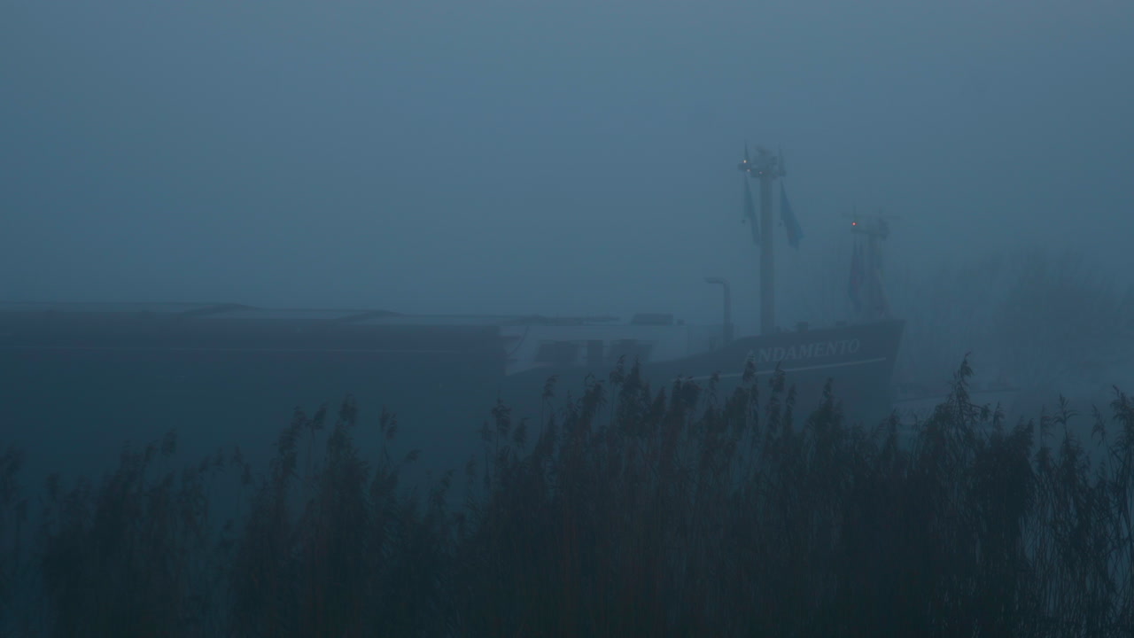 buque granelero navegando en la misteriosa niebla matutina, cruzando la bahía de transbordadores de genemuiden, países bajos