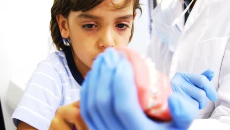 dentista mostrando a un paciente joven cómo cepillarse los dientes