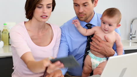 parents using laptop with their baby son and calculating bills